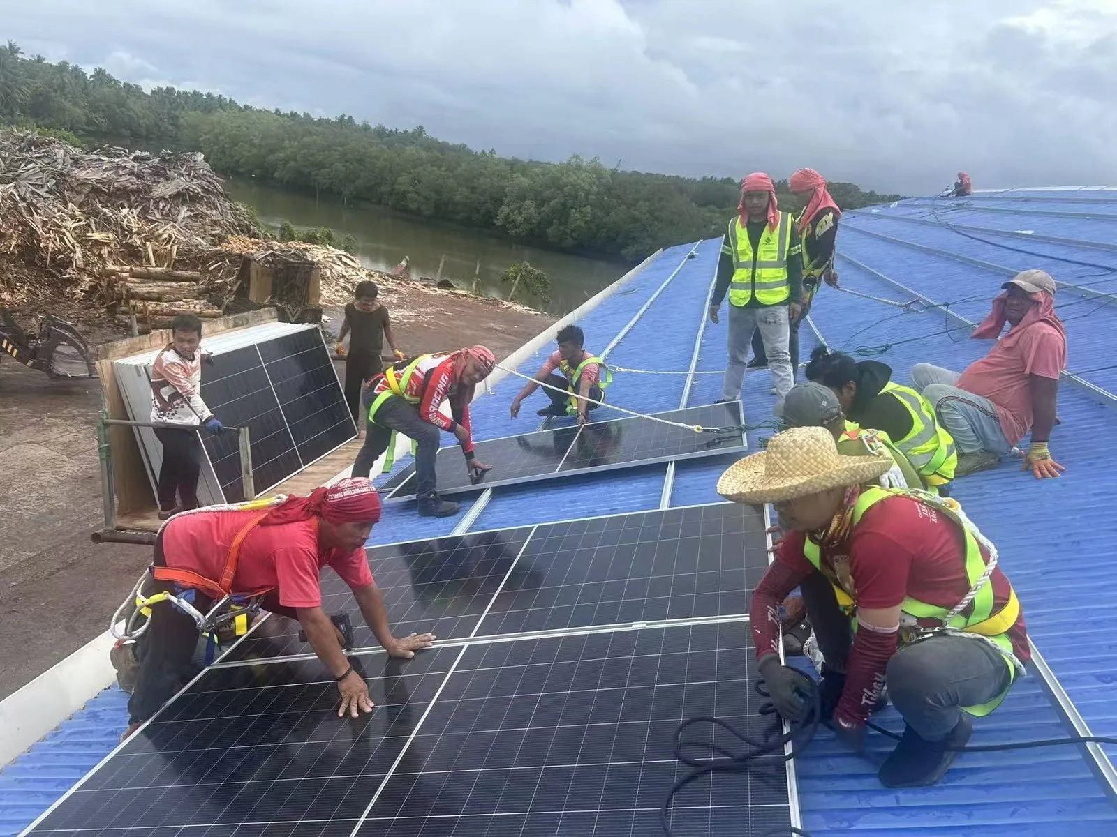 Installation crew mounting solar panels row by row on the factory roof